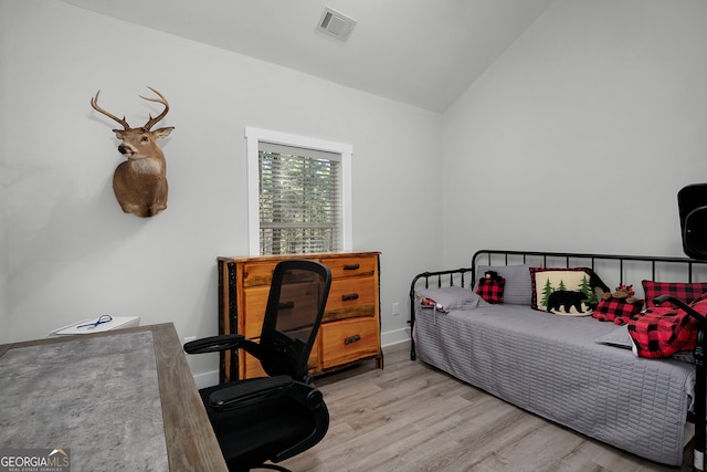 bedroom with light wood-type flooring and lofted ceiling