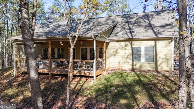 back of property with a sunroom, ceiling fan, and a deck