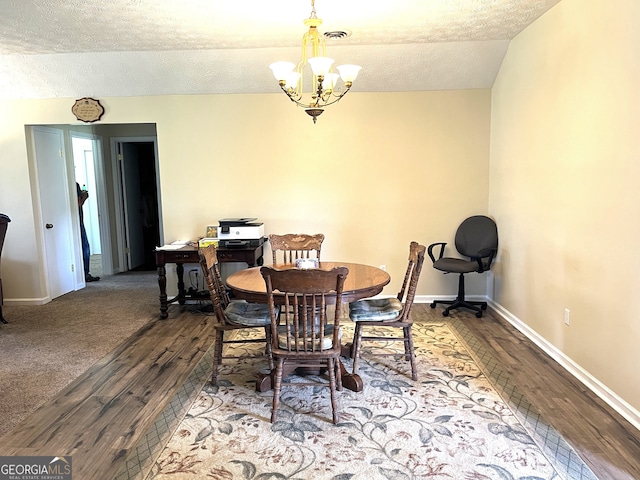 dining room featuring an inviting chandelier, hardwood / wood-style floors, vaulted ceiling, and a textured ceiling