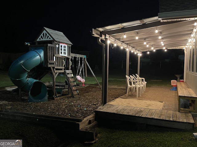 yard at night with a playground and a deck