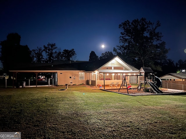 back house at twilight featuring a playground and a yard