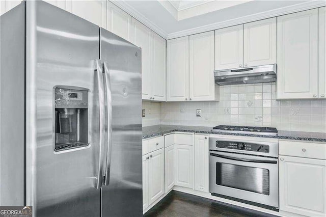 kitchen featuring decorative backsplash, stainless steel appliances, crown molding, dark stone countertops, and white cabinets