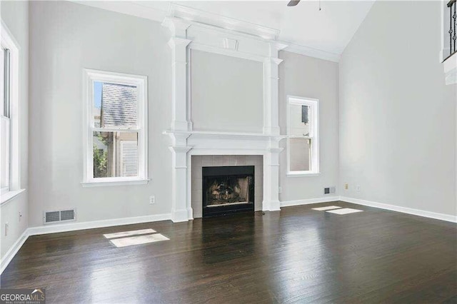 unfurnished living room featuring ceiling fan, dark wood-type flooring, crown molding, lofted ceiling, and a fireplace