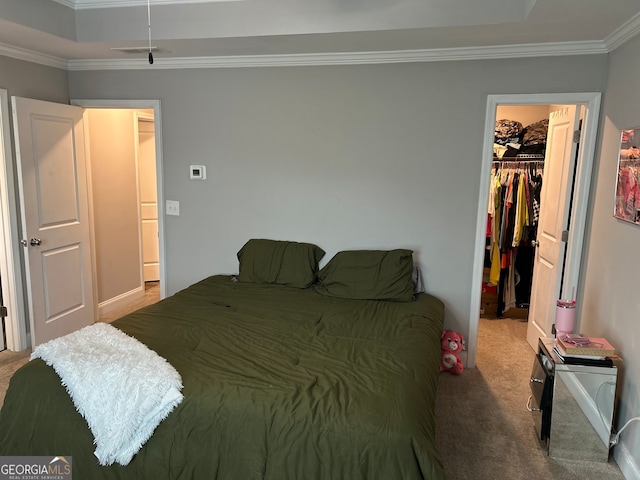 carpeted bedroom with a closet, a walk in closet, and ornamental molding