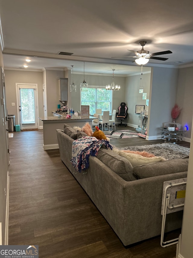 living room with a wealth of natural light, ceiling fan with notable chandelier, dark hardwood / wood-style floors, and crown molding