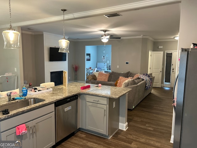 kitchen featuring a fireplace, light stone countertops, hanging light fixtures, and stainless steel appliances