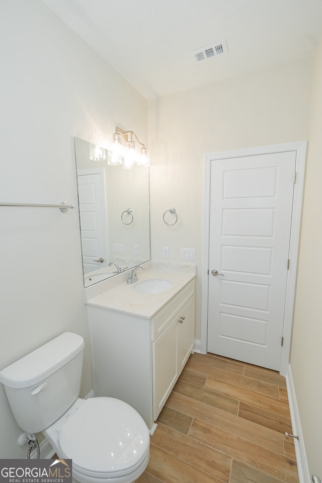 bathroom with wood-type flooring, toilet, and vanity