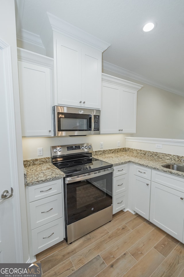 kitchen featuring ornamental molding, stainless steel appliances, light wood-type flooring, white cabinetry, and light stone countertops