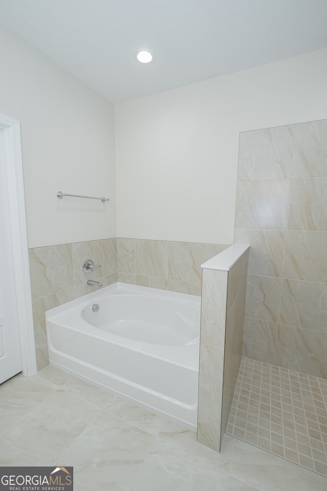 bathroom with shower with separate bathtub and tile walls