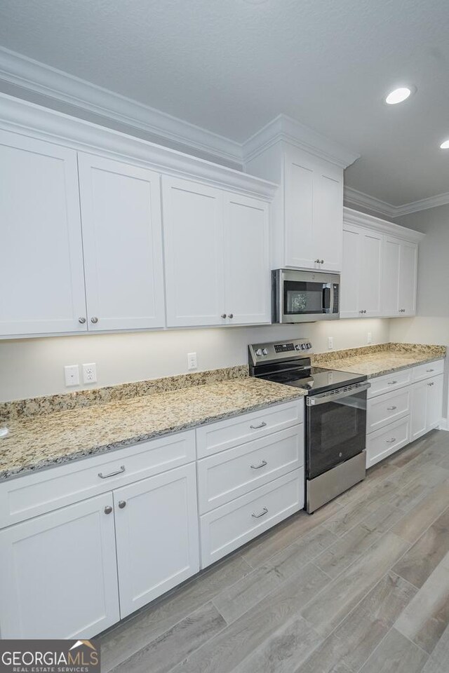 184 The Villas Way, Kingsland, GA 31548 - kitchen featuring light stone counters, white cabinets, light hardwood / wood-style flooring, ornamental molding, and appliances with stainless steel finishes