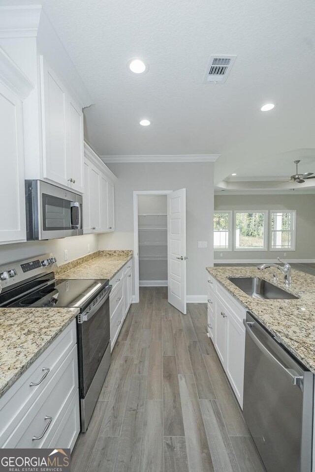 184 The Villas Way, Kingsland, GA 31548 - kitchen with stainless steel appliances, white cabinets, sink, and light hardwood / wood-style flooring