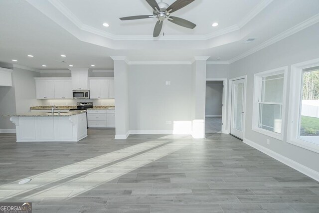 184 The Villas Way, Kingsland, GA 31548 - kitchen featuring ornamental molding, a kitchen island with sink, light stone countertops, white cabinetry, and appliances with stainless steel finishes