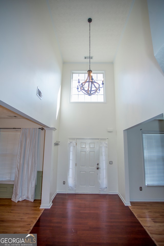 entryway featuring a towering ceiling, dark hardwood / wood-style flooring, and a notable chandelier