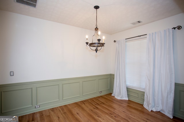 unfurnished room featuring hardwood / wood-style flooring and a notable chandelier