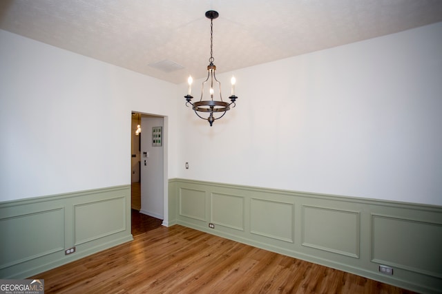 spare room featuring hardwood / wood-style flooring and a notable chandelier