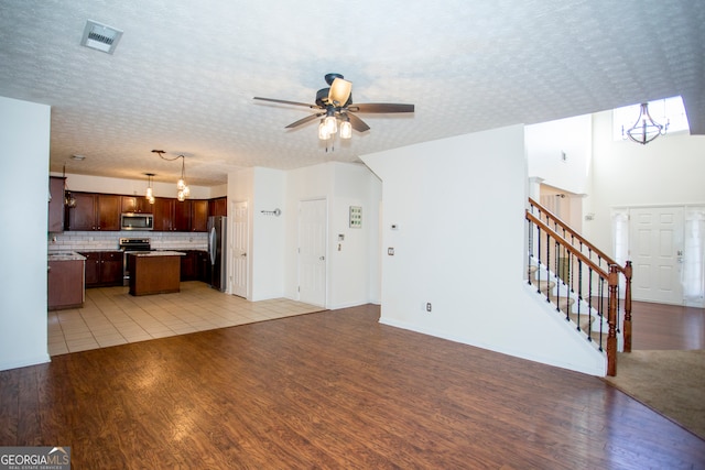 unfurnished living room with light wood-type flooring, a textured ceiling, and ceiling fan