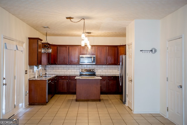 kitchen with pendant lighting, decorative backsplash, appliances with stainless steel finishes, and a center island