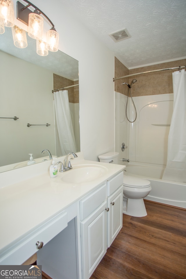 full bathroom featuring shower / bath combination with curtain, vanity, a textured ceiling, hardwood / wood-style floors, and toilet