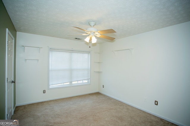 carpeted spare room featuring ceiling fan and a textured ceiling