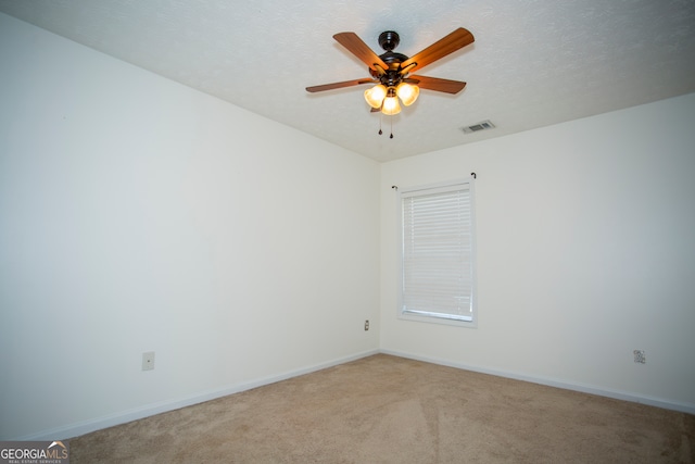 empty room with ceiling fan, a textured ceiling, and carpet flooring