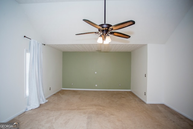 empty room featuring plenty of natural light, ceiling fan, light colored carpet, and vaulted ceiling