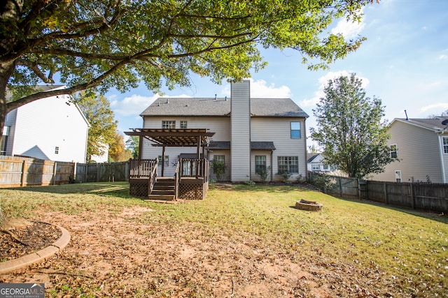 rear view of property with a lawn, an outdoor fire pit, and a wooden deck