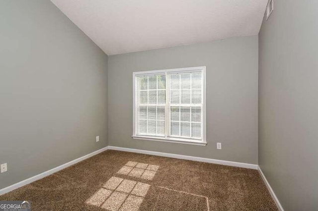 carpeted spare room with vaulted ceiling