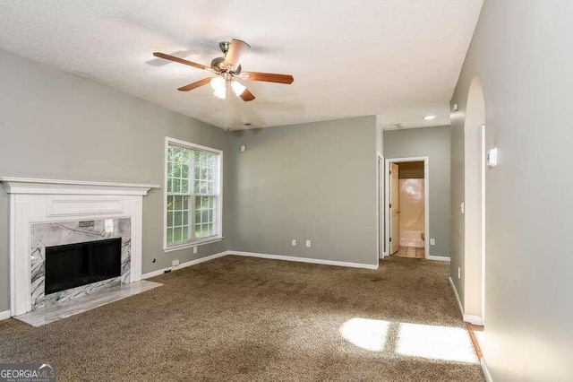 unfurnished living room with carpet, ceiling fan, and a high end fireplace