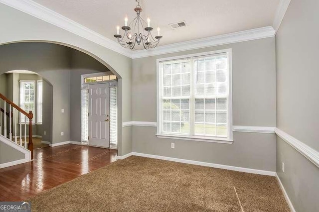 foyer entrance featuring ornamental molding, dark wood-type flooring, and a notable chandelier