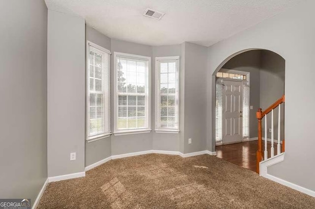 entryway featuring dark colored carpet and a textured ceiling