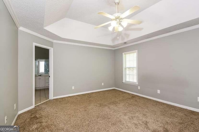 carpeted spare room with a textured ceiling, ceiling fan, crown molding, and a tray ceiling