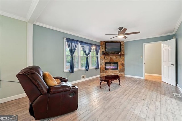 living room with a fireplace, light hardwood / wood-style floors, ceiling fan, and crown molding