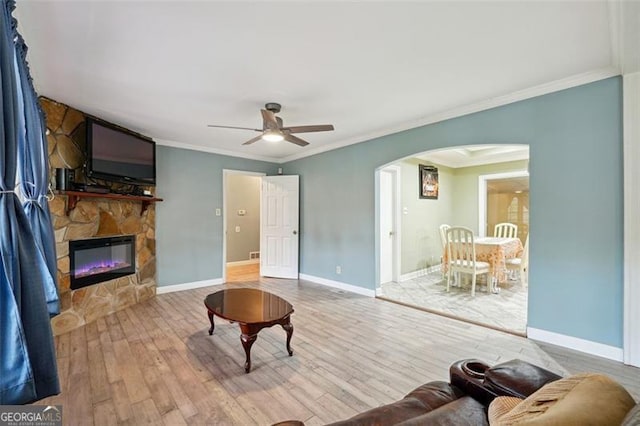 living room featuring ornamental molding, a fireplace, wood-type flooring, and ceiling fan