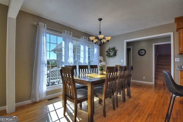 dining room with an inviting chandelier, a textured ceiling, and light wood-type flooring