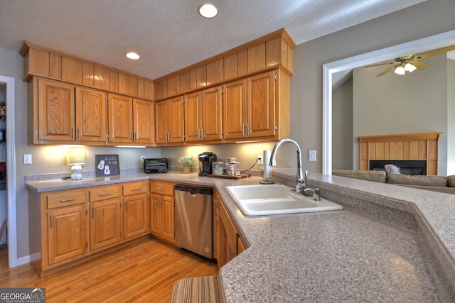 kitchen with light hardwood / wood-style floors, dishwasher, a textured ceiling, sink, and a fireplace