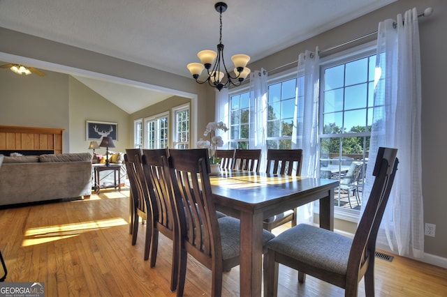 dining space with lofted ceiling, light hardwood / wood-style floors, and ceiling fan with notable chandelier