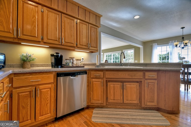 kitchen with a notable chandelier, pendant lighting, sink, stainless steel dishwasher, and light hardwood / wood-style flooring