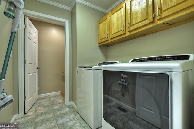 clothes washing area featuring ornamental molding, washing machine and dryer, cabinet space, and baseboards