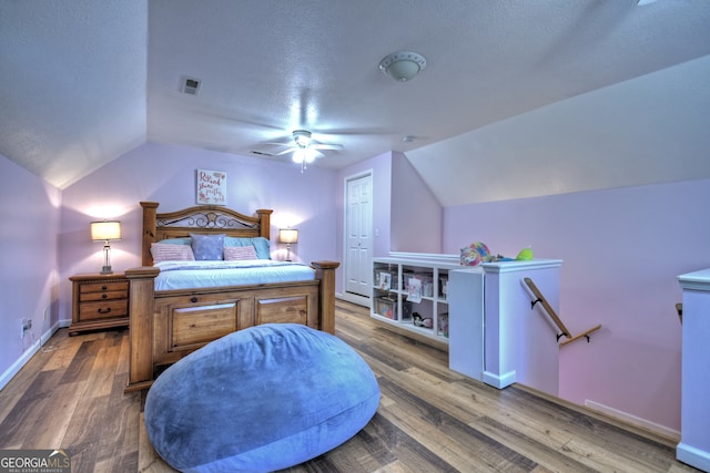 bedroom featuring a textured ceiling, hardwood / wood-style floors, ceiling fan, and vaulted ceiling