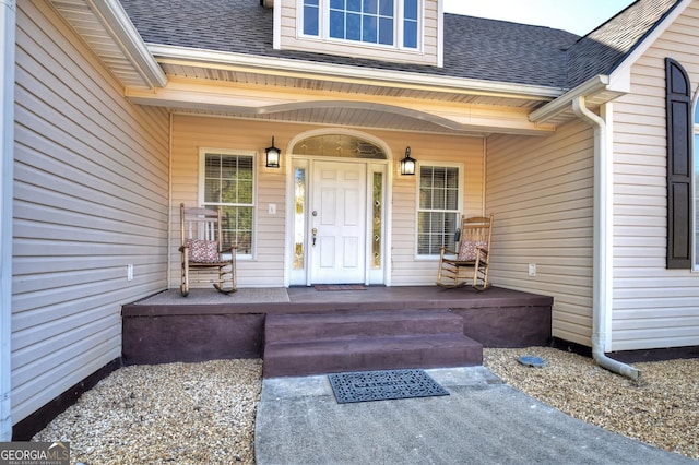 doorway to property with a shingled roof and a porch