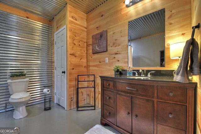 bathroom with concrete flooring, wood walls, toilet, and vanity