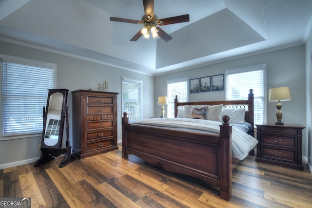 bedroom with ceiling fan, dark hardwood / wood-style floors, a raised ceiling, and ornamental molding