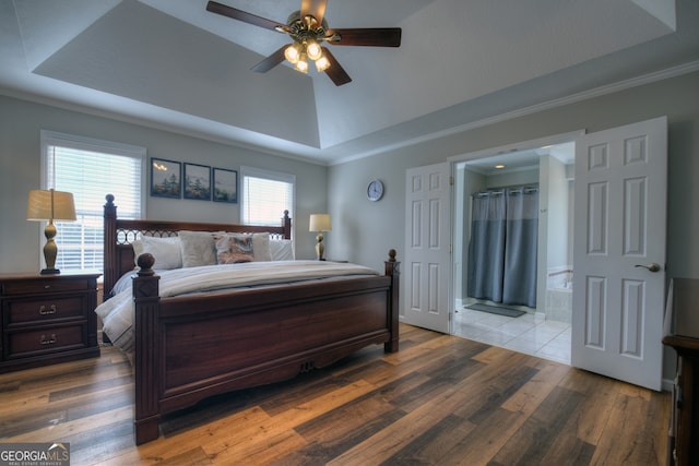 bedroom featuring ensuite bathroom, wood-type flooring, multiple windows, and ceiling fan