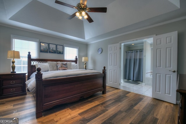 bedroom with ensuite bathroom, wood finished floors, a ceiling fan, ornamental molding, and a tray ceiling