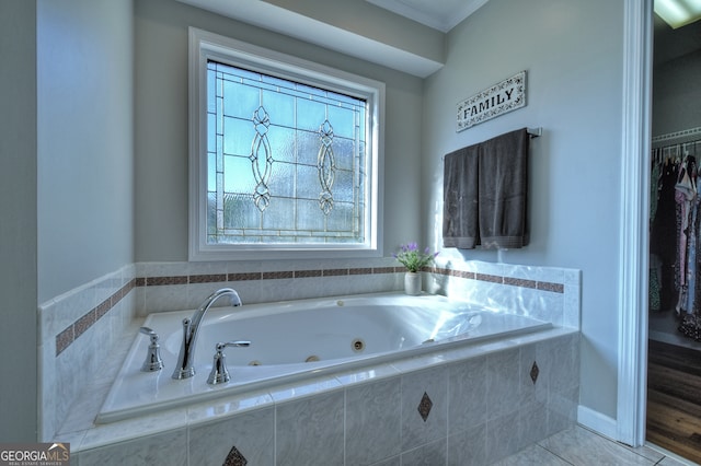 bathroom featuring tile patterned floors, crown molding, and tiled tub