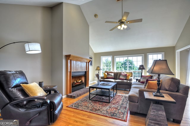 living room featuring hardwood / wood-style floors, a fireplace, ceiling fan, and high vaulted ceiling