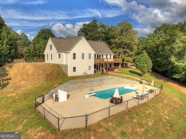 view of swimming pool with a diving board, a lawn, and a patio area