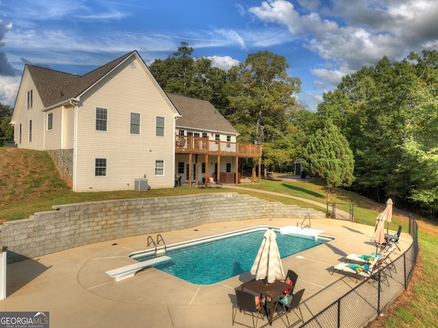 view of pool with central air condition unit, a patio, a deck, a diving board, and a lawn