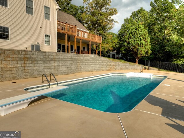 view of swimming pool with a fenced in pool, a patio area, central AC, fence, and a diving board