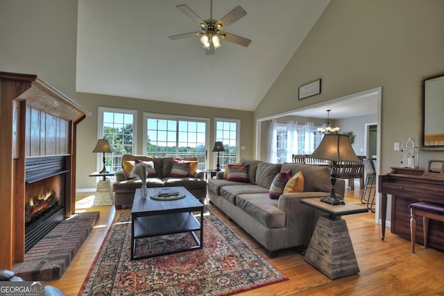 living room with high vaulted ceiling, a fireplace, a healthy amount of sunlight, and light hardwood / wood-style flooring